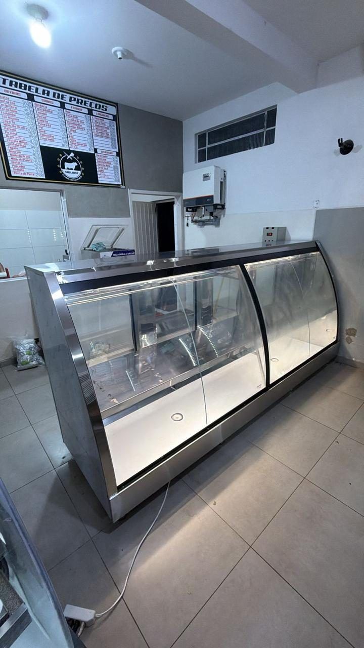 Detalhe do acabamento em aço inox e do vidro curvo do balcão refrigerado fabricado sob medida